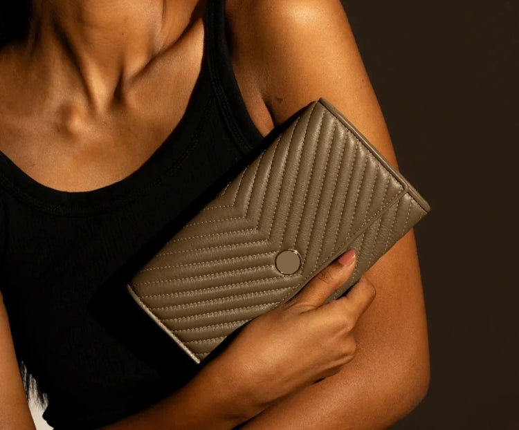 Person holding a textured clutch bag against a dark background